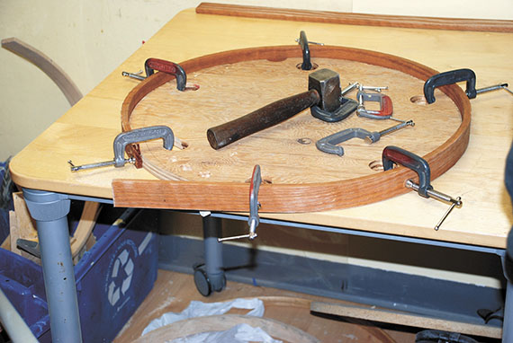 The wood for the drum head being fastened to the template. The wood was softened for two days in a steamer, which allowed the wood to bend.