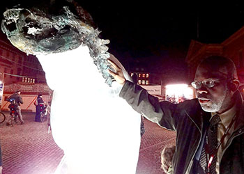 Expect nothing from the United Nations climate change conference in Copenhagen, Cletus Springer of St. Lucia, a small Caribbean island beset by increasing numbers of hurricanes and rising sea levels, said this week. In this picture, Springer stands beside the WWF's ice carving of a polar bear, which is melting as the conference wears on. (PHOTO BY JANE GEORGE)