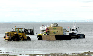 A forklift truck ventures out at low tide to offload pallets from a barge carrying goods brought to Iqaluit by a ship that's anchored further down the bay. Iqaluit’s dangerously inadequate staging area for sealift cargo needs big improvements, Suzanne Paquin, the chief executive officer and president of Nunavut Eastern Arctic Shipping Inc. told Nunatsiaq News this week. (FILE PHOTO)