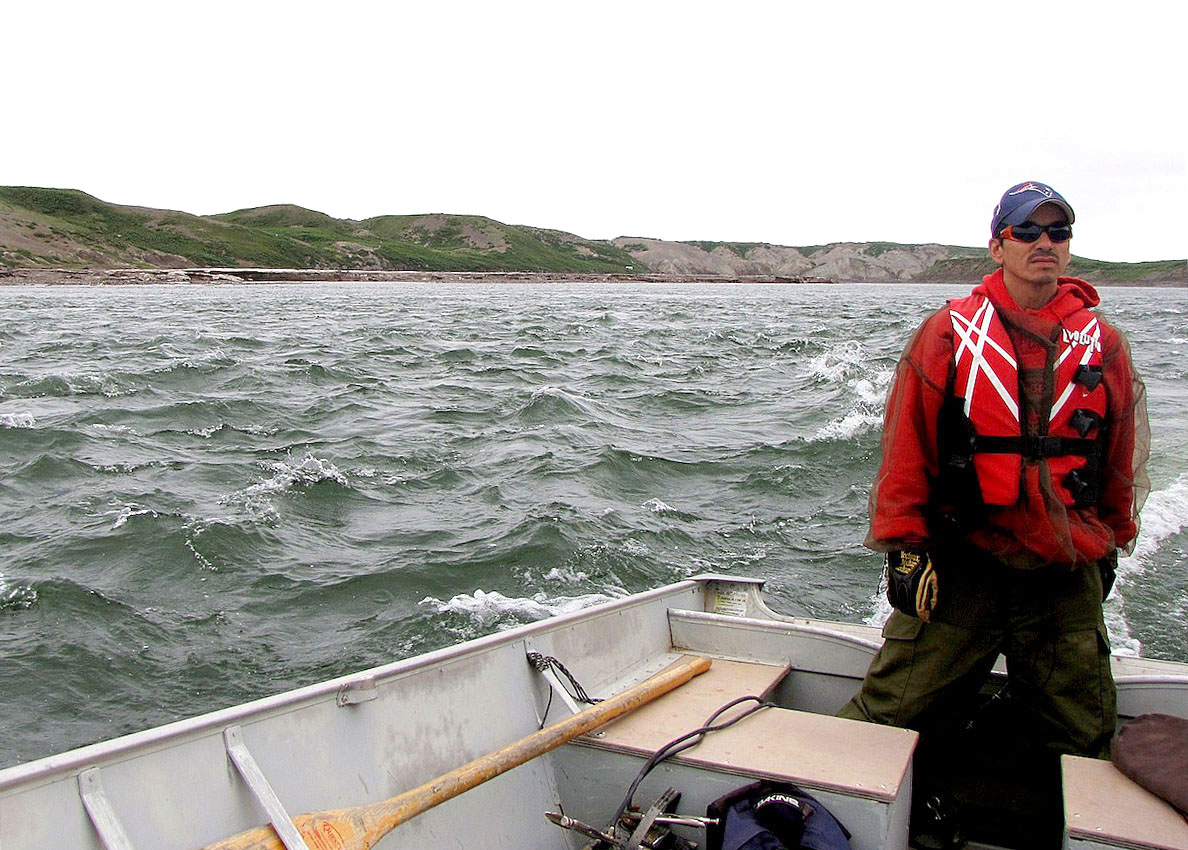 Guide Kenny Kuodluak stands at the helm of the boat that takes researcher Crystal Ernst to the Coppermine River for aquatic sampling of insects near Kugluktuk. (PHOTO BY CRYSTAL ERNST) 