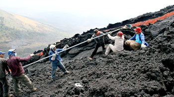 Guatemalan assistants muscle a long ladle with a bronze mold into a lava flow during an eruption of Mount Payaca in the highlands of Guatemala.