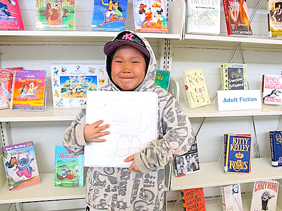 Cambridge Bay’s May Hakongak Library is encouraging kids to read through its “Reading Rocks” competition, sponsored by the local stores. Here, Nicholas Ekpakohalok holds up his winning “Reading Rocks” binder. Nicholas, like other Reading Rocks participants, agreed to read 10 books. Every time he read a book, he wrote the title in an inuksuk rock page in his binder. Once he read 10, he got to choose a prize, and put his name into a draw. Every week the library choses two name from this pot, and one winner wins a gift certificate from the Co-Op and the other wins one from the Northern. (PHOTO COURTESY OF THE KITIKMEOT HERITAGE SOCIETY)