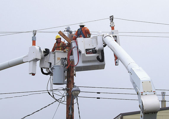 Qulliq Energy Corp. linemen work on a power pole Aug. 7. The work, part of a project to upgrade QEC's transmission lines, caused a short power outage in the Tundra Ridge area of Iqaluit. (PHOTO BY CHRIS WINDEYER)