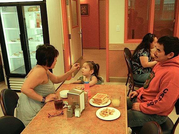 Two-year-old Chasity Tucktoo-Ruben of Taloyoak, shown here with her mother, Colleen, and father Adam, is eager for breakfast at Larga Kitkmeot in Yellowknife. Larga Kitikmeot — just about the same age as little Chasity —  is often full with 56 residents in its 28 hotel-like double bedrooms. (PHOTO BY JANE GEORGE)