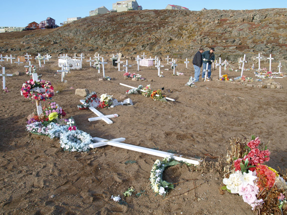 Iqaluit city workers replace one of 25 crosses toppled by vandals at Iqaluit's cemetery Sept. 19. None of the crosses appeared to be damaged, but were pulled out of the ground. (PHOTO BY CHRIS WINDEYER)