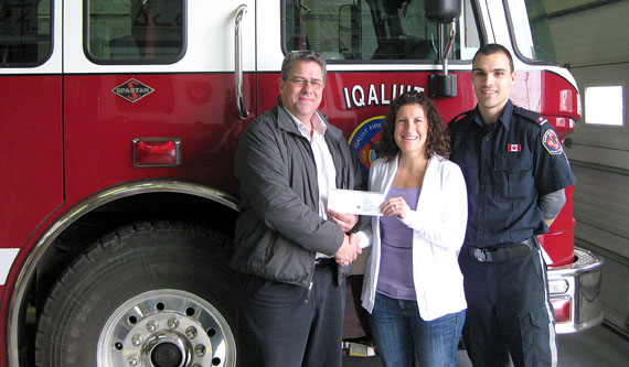 Sharon MacDonald and FF Mark Dainton of the Iqaluit Firefighter's Association present a cheque for $1,800 to Glenn Cousins of Habitat for Humanity Iqaluit. The firefighters raised the money during their annual Rubber Duck Race in July and also made a donation to The Sunshine Foundation, which helps grant wishes to sick and disabled children. (PHOTO COURTESY OF SHARON MACDONALD)