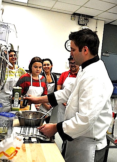 Inuksuk High School students watch as instructor Aaron Watson, right, seasons his fresh-cut salsa. Watson says his goal as a volunteer with Skills Nunavut is to teach his class to make “good, homemade food.” (PHOTO BY SARAH ROGERS)