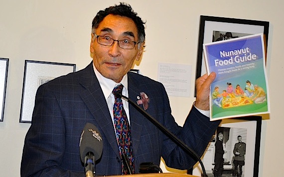 Nunavut's health and social services minister Tagak Curley shows off the new Nunavut food guide at its launch Oct. 26 at the legislative assembly. The guide — the first updated version since 2002 — stresses the “importance of sharing country food with children at a young age,” he said. (PHOTO BY SARAH ROGERS)