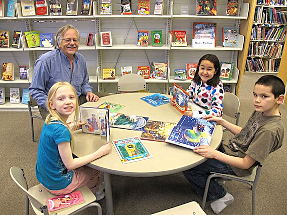 Nothing better than a holiday story: Paul Tanner and students from his Grade 3 class at Kullik Ilihakvik take a look at Christmas-themed books at Cambridge Bay's May Hakongak library. (PHOTO BY R. KRUCAS)