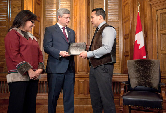 Pujjuut Kusugak, the mayor of Rankin Inlet, gives Prime Minister Stephen Harper a sealskin notebook Feb. 2 as Nunavut MP Leona Aglukkaq looks on, in a public relations event held as part of