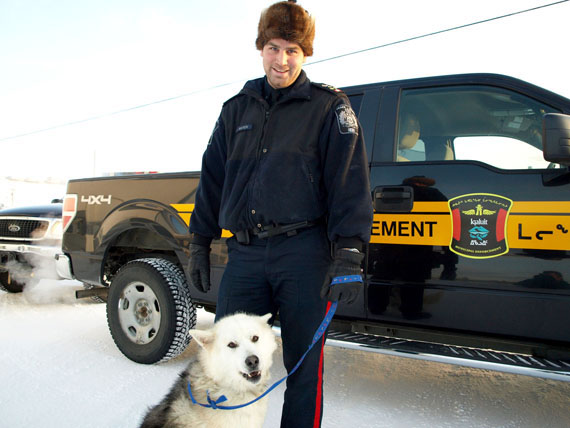 Michael Hatch, Iqaluit’s acting chief bylaw enforcement officer, stands with a husky dog that bylaw officers recently picked up. Hatch estimates that his department picks up about 20 loose dogs each month, with about half of those returned to owners. The others are either given up for adoption or destroyed if deemed aggression. (PHOTO BY DEAN MORRISON)
