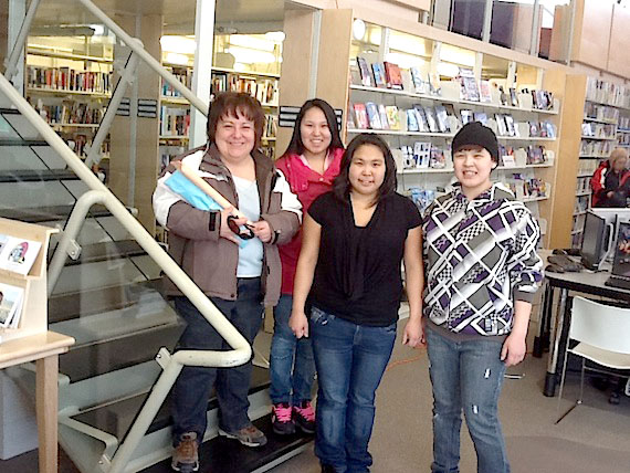 Denise LeBleu of Cambridge Bay holds a $6 bunch of daffodils (wrapped up in paper so they don't freeze outside), along with volunteer daffodil-sellers and students Donna Lyall, Chelsea Kavanna and Amanda Pauloosie. Volunteers are selling the 10-flower bunches of daffodils around Cambridge Bay and at Kiilinik High School on March 22 to celebrate spring and help raise money to fight cancer. (SUBMITTED PHOTO)