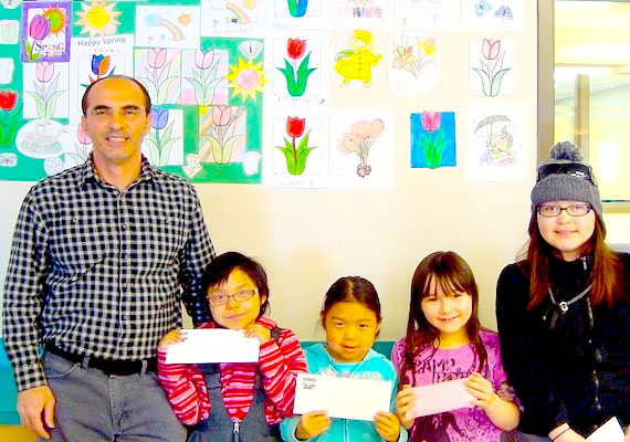 Kugluktuk librarian Reza Behboudi poses with the winners of the library's spring contest which produced enough tulips and other flowers to fill an entire wall. (PHOTO COURTESY OF THE KUGLUKTUK LIBRARY)