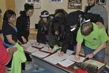 Katimavik youth volunteers in Iqaluit sign up April 4 to help with Toonik Tyme as Janet Brewster (left), the president of Toonik Tyme’s board, looks on. (PHOTO BY JANE GEORGE) 