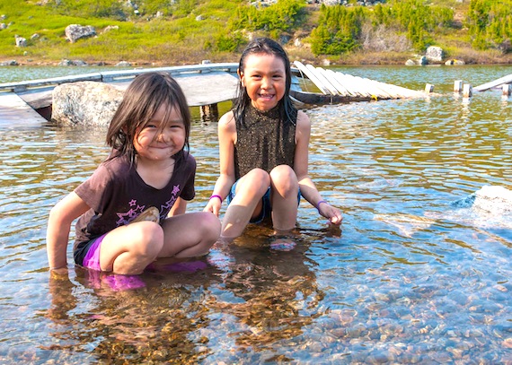 Sisters Desiree and Echo Imak cool off in the lake June 12 in Kangiqsualujjuaq, where temperatures reached 25 C with a humidex of 33 C. With the community's municipal pool still closed, many kids were willing to walk five kilometres to Alan's Lake for a dip. (PHOTO BY PASCAL POULIN)