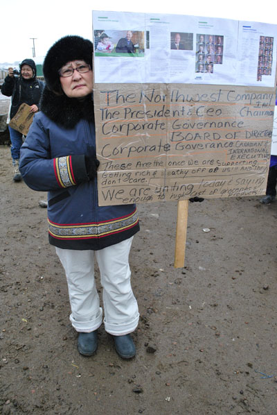 Veronica Dewar of Iqaluit carries a sign bearing a message about the CEO and board of directors of the North West Co. (PHOTO BY JIM BELL)