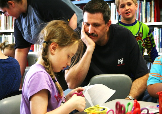 Jeff Chown watches as his eight-year-old daughter Lena makes him a Father's Day present June 16 at the Centennial Library where was a special Inuktitut and English Father's Day-themed family story time that included songs, crafts and activities. (PHOTO BY DAVID MURPHY)