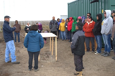A group of people from Clyde River listen to engineer Jan Wiid speak about the radar towers installed near their community which will help track