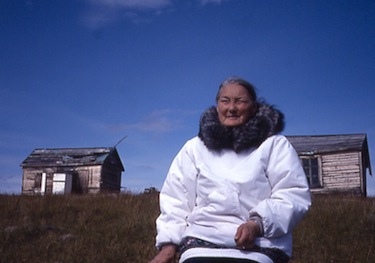 Tuinnaq Kanayuk Bruce sits in front of the former trading post and house at Wager Bay, which now lies inside Ukkusiksalik National Park. (PHOTO BY DAVID PELLY)