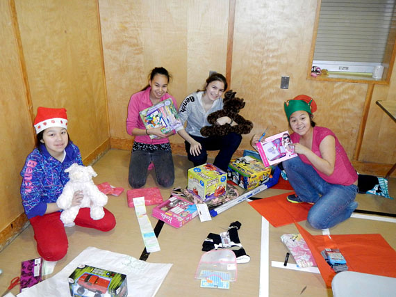 From left to right: Minnie Parr, Moosie Toonoo, Carmen Rowsel and Leeta Qimirpik, some of the young people in Cape Dorset’s youth mentorship program, help wrap gifts for kids. All of the items will be packed into gift baskets and delivered to families in need in the community. (PHOTO COURTESY C. WADDELL) 

