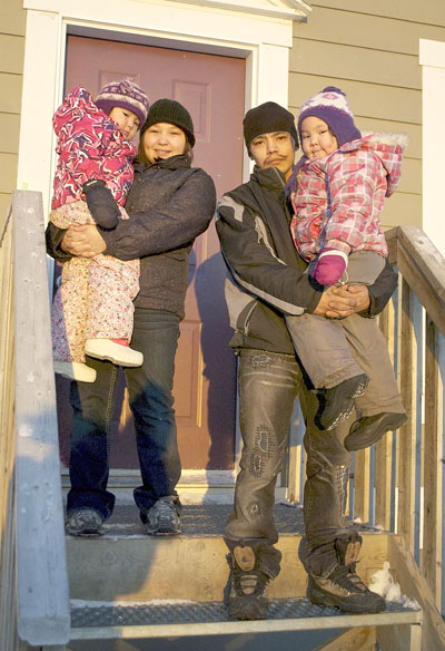 Eepeebee Campbell in front of his housing unit with his common-law partner, Debbie Kippomee, who is holding three-year-old Della Kippomee. Campbell is holding five-year Elaine Kippomee. (PHOTO BY BRIELLE MORGAN)