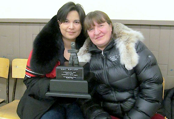 Tanya Tungilik, sitting with her mother, Johanne Autut, holds a plaque she accepted on behalf of her father, the late Marius Tungilik, this week in Rankin Inlet. The inscription reads: