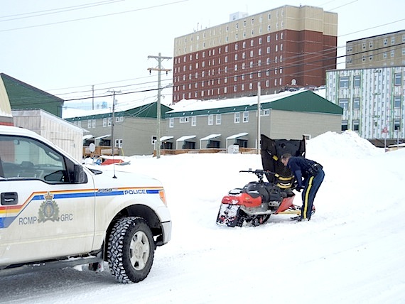 A member of the RCMP checks out a snowmobile that's been abandoned — possible after being stolen — on an Iqaluit street. (PHOTO BY JANE GEORGE)