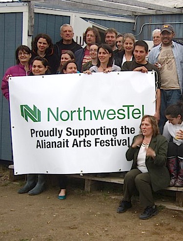 Northwestel volunteers in Iqaluit hold up a sign showing their support as volunteers from the city's Alianait arts festival. (HANDOUT PHOTO)
