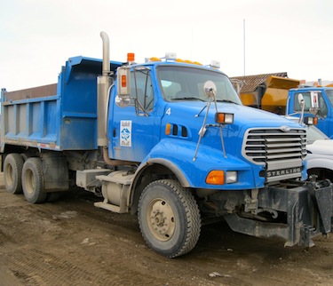Iqaluit's public works department aims to reduce the variety of makes in its fleet of trucks, pictured, and other equipment in an effort to reduce maintenance costs. The department ordered a new backhoe and two heavy trucks from the Toromont Cat dealer in Iqaluit this month, ready for use this summer. (PHOTO BY PETER VARGA)