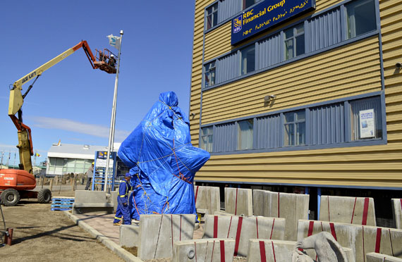Workers make last-minute touch-ups July 8 to the site in front of the Igluvut building in Iqaluit that holds a monument to the Nunavut Land Claims Agreement made by three master carvers: Inuk Charlie of Taloyoak, Paul Malliki of Repulse Bay and Looty Pijamini of Grise Fiord. An assemblage of Nunavut politicians will mark the 20th anniversary of the agreement at a ceremony to be held there between 12 noon and 1:00 p.m. July 9, when they'll pull the blue cover off the monument. Iqaluit residents can also enjoy an air show at the Iqaluit airport and a feast, barbecue, games and dancing near the Igluvut building. The Nunavut Arts and Crafts Association will hold their closing exhibition at the cadet hall between 4:00 p.m. and 7:00 p.m. and an Inuktitut film festival will be held at the Astro Theatre between 7:00 p.m. and 11:00 p.m. (PHOTO BY JIM BELL)