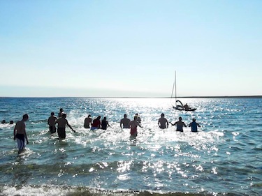 Under clear, sunny skies, swimmers in Cambridge Bay head into the waters by the community to raise money for a new recreational complex. (PHOTO BY JEANNIE EVALIK)