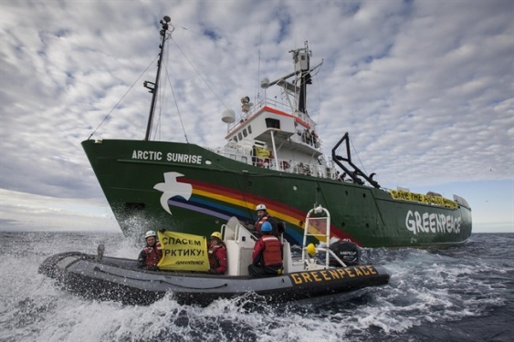 Greenpeace activists on board a zodiac near the Arctic Sunrise in Russia's Arctic waters this past August protest offshore oil drilling there. Shortly afterwards, Russian Coast Guard officials boarded the vessel. (PHOTO COURTESY OF GREENPEACE)