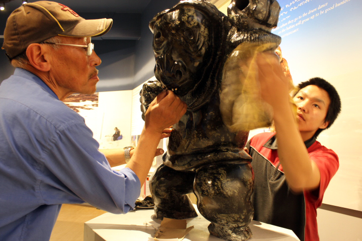 Gjoa Haven master carver Uriash Puqiqnak inserts caribou antler teeth into his sculpture, while his student, Moses Totalik completes the finishing polish. Puqiqnak's piece will go on display at the community's new Nattilik Heritage Centre, which opens its doors Oct. 17. Read more about the new centre on Nunatsiaqonline.ca. (PHOTO BY ED STEWART) 