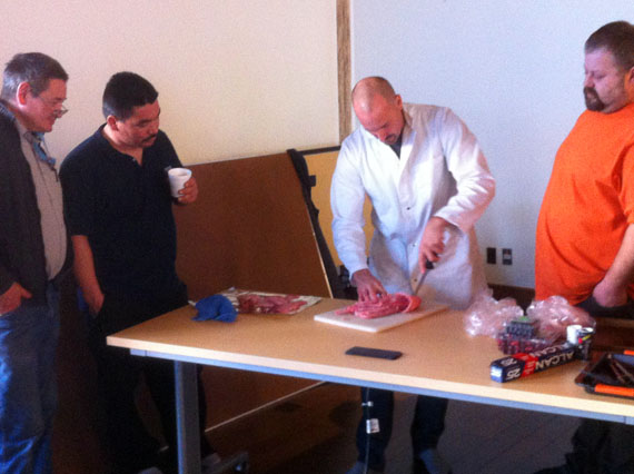 Jean-François Audet, centre, a rabbit producer and butcher from outside of Quebec City, shows onlookers how to carve a rabbit at a workshop hosted by the KRG in Salluit Nov.21. (PHOTO COURTESY OF THE KRG)