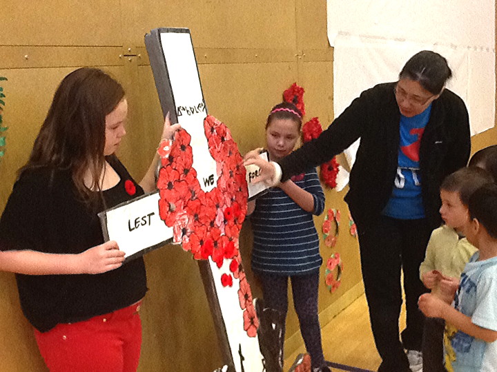 With the Remembrance Day holiday coming up on Monday, Nov. 11, students around the territory are celebrating the sacrifice made by Canada's Armed Forces over the years. Here, Joamie Iliniarvik School teacher Lena Ipeelie helps students pin their poppies on a cross. (PHOTO BY SONJA LEBLANC)
