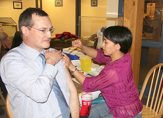 Keith Peterson, Nunavut's finance minister, gets a flu shot from public health nurse Susie Pearce in 2013 at the Nunavut Legislative Assembly building in Iqaluit. (FILE PHOTO)