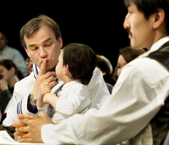 Ed Picco, then the MLA for Iqaluit East, soothes a child while Paul Okalik, then the MLA for Iqaluit West, waits for Nunavut's first legislative assembly sitting to get started on April 1, 1999 inside the Inuksuk High School gymnasium in Iqaluit. (FILE PHOTO)