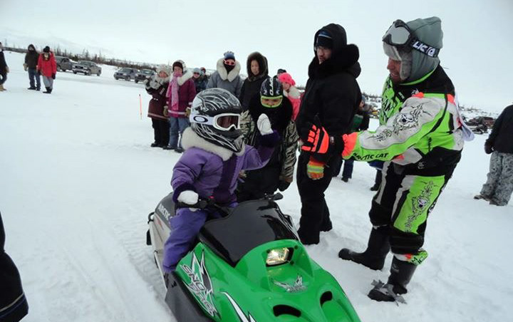 Six-year-old snowmobiler Amy May gives a high five to George Kauki at Stewart Lake (Tasialuk) in Kuujjuaq April 5. Kauki, the local youth committee president, helped organize races for Kuujjuaq's young riders last weekend; this weekend, men's and women's oval races take place at Stewart Lake April 12. (PHOTO BY SIQUAQ TUKKIAPIK) 
