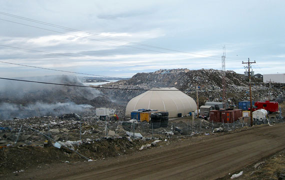 Iqaluit’s dump fire smoulders away within a pile more than two storeys high, left, at the city’s landfill site June 8. The fire department says the blaze is under control and in no danger of spreading to the second pile on the right. Smoke blowing into the city with westerly winds has caused school closures and health concerns among residents. The Government of Nunavut and City of Iqaluit now say they're working on a plan with Health Canada and Environment Canada to measure air quality in the city. (PHOTO BY PETER VARGA)