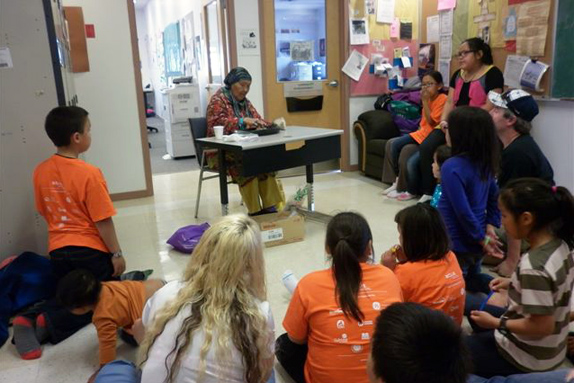 Cambridge Bay children and parents gather around elder Eva Kakolak Avadluk as she lights the qulliq for the closing event and graduation of the ACTUA mini health science camp. The camp, which runs in different Nunavut communities each year, is supported by the department of Health and Social Services, and designed to promote health science careers and healthy living to Inuit youth. (PHOTO COURTESY OF NAC)