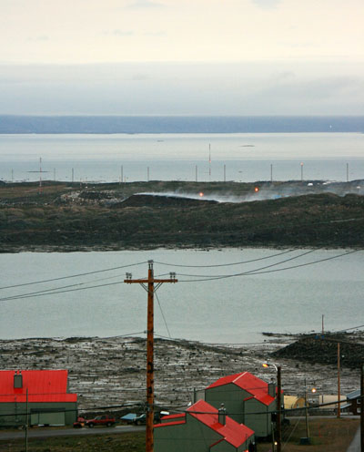 Iqaluit’s dump fire throws off steam on a wet evening Aug. 6 opposite Koojesse Inlet from the city. Firefighters promise to throw a whole lot more water on the smouldering heap when an extinguishing plan begins in late August. (PHOTO BY PETER VARGA)