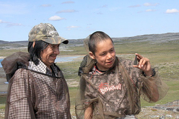 Autsalik Naqtai, right, holds up a milky quartz microblade and a polished slate point he unearthed at a field survey site north of Inukjuak. Naqtai is one of several youth taking part in an archaeological excavation at sites around the community, led by the Avataq Cultural Institute. The blades Naqtai found are likely Paleoeskimo-era knives or hunting lances, Avataq said. (PHOTO COURTESY OF AVATAQ)