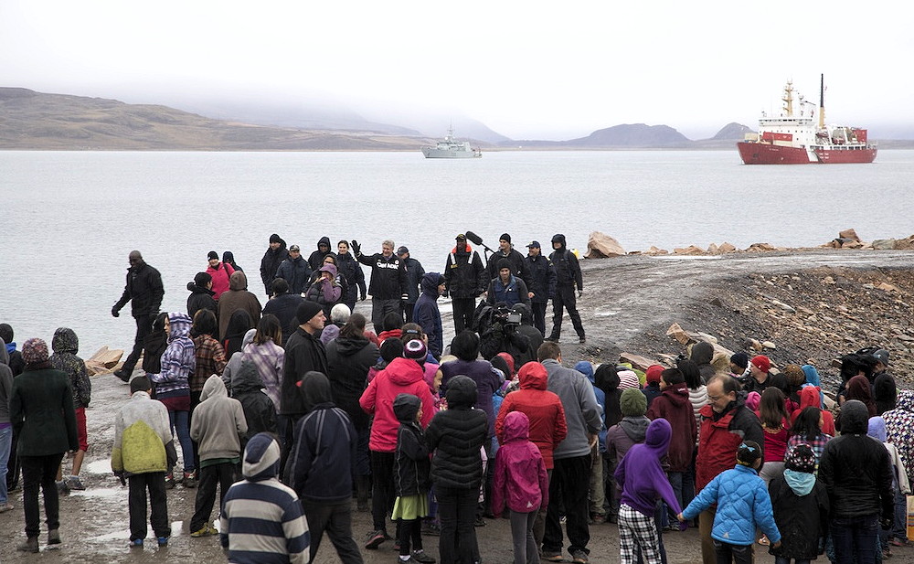 Prime Minister Stephen Harper, waving in middle, greets people in Arctic Bay during a brief stop in that North Baffin community Aug. 25 during his annual northern tour. According to local reports, he took a walk on the breakwater, spent about a half-hour meeting residents, then left by helicopter for Pond Inlet. The HMCS Kingston and the CCGS Des Groseilliers lie in the background. Harper is expected to arrive in Iqaluit later today, Aug. 25. (PHOTO BY CLARE KINES)