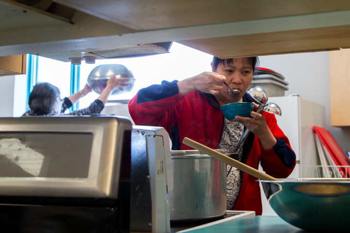 Emily Chapple taste-tests char chowder Mar. 22, while Bessie Sitatak prepares bannock in the Kugluktuk High School kitchen. (PHOTO BY JESSE AJAYI)