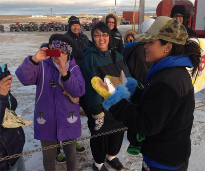 Ariel Tweto receives a warm welcome and handmade pair of mitts from residents of Taloyoak Sept. 21. The Inupiaq TV star and motivational speaker is touring the Kitikmeot region this month. (PHOTO COURTESY OF POPPING BUBBLES)