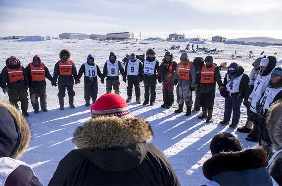 Ivakkak mushers and officials gather to say a morning prayer March 24 before teams set off from Inukjuak to complete the last leg of the 2015 edition of Nunavik's dog sleg race. Dog teams are expected to begin arriving at the finish line in neighbouring Puvirnituq March 26. (PHOTO BY SANDY ETOK)
