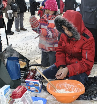 Hannah Kiguktak works fast at the Toonik Tyme festival’s tea and bannock contest, April 4 in Iqaluit, as her daughter Hailey looks on. (PHOTO BY PETER VARGA)