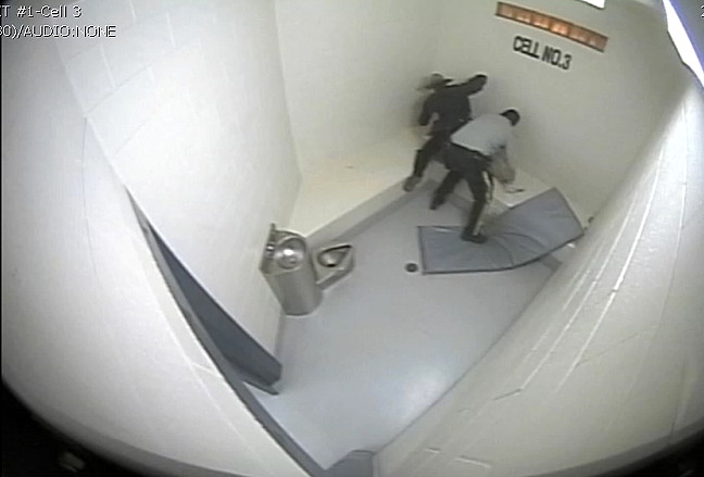 One member of the Nunavut RCMP holds down Bernard Naulalik's legs and another member sits on the prisoner's chest while winding up to deliver a blow to Naulalik's head or neck. The three charges Naulalik faced from July 18, 2014 were stayed by the Crown after his defence lawyer filed a Charter application alleging