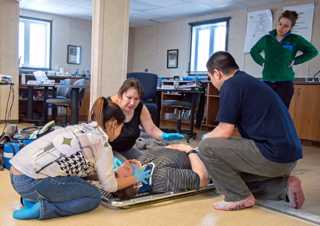 Don't forget to stabilize the head! Cambridge Bay residents Jessie Tologanak, black shirt, Tracy Okhina, white shirt, and Sandy Ng, blue shirt, apply their emergency responder training to a distressed