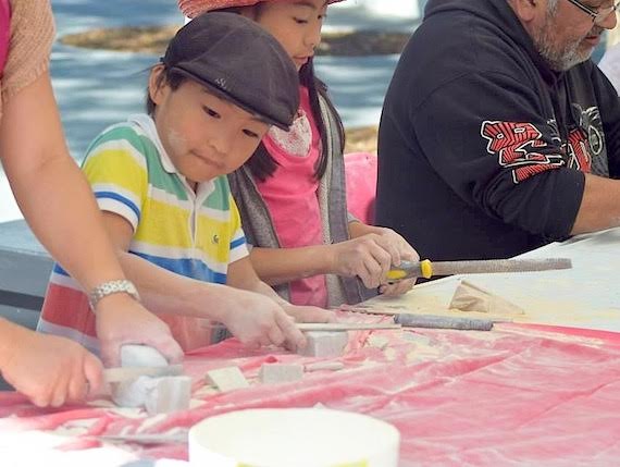 A youngster works on a piece of soapstone Aug. 7 at Montreal's Cabot Square, located at the corner of Ste-Catherine Street West and Atwater Avenue. Inuit youth at risk have been leading carving workshops at the park this summer, coordinated through Projet Autochtone du Quebec and the Native Friendship Centre of Montreal, and funded by Makivik Corp. The workshops fall under the newly-launched Cabot Square Project, which offers services and programming for the well-being of urban Aboriginal and Inuit residents.  (PHOTO BY NAN GOLDSKIN/CABOT SQUARE PROJECT) 